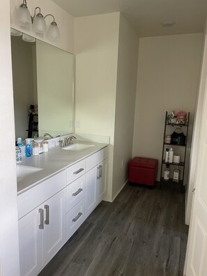 A modern bathroom with a white vanity, dual sinks, and a large mirror.