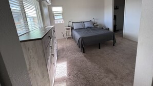 A bedroom with a bed, bedside table, lamp, and a ceiling fan.