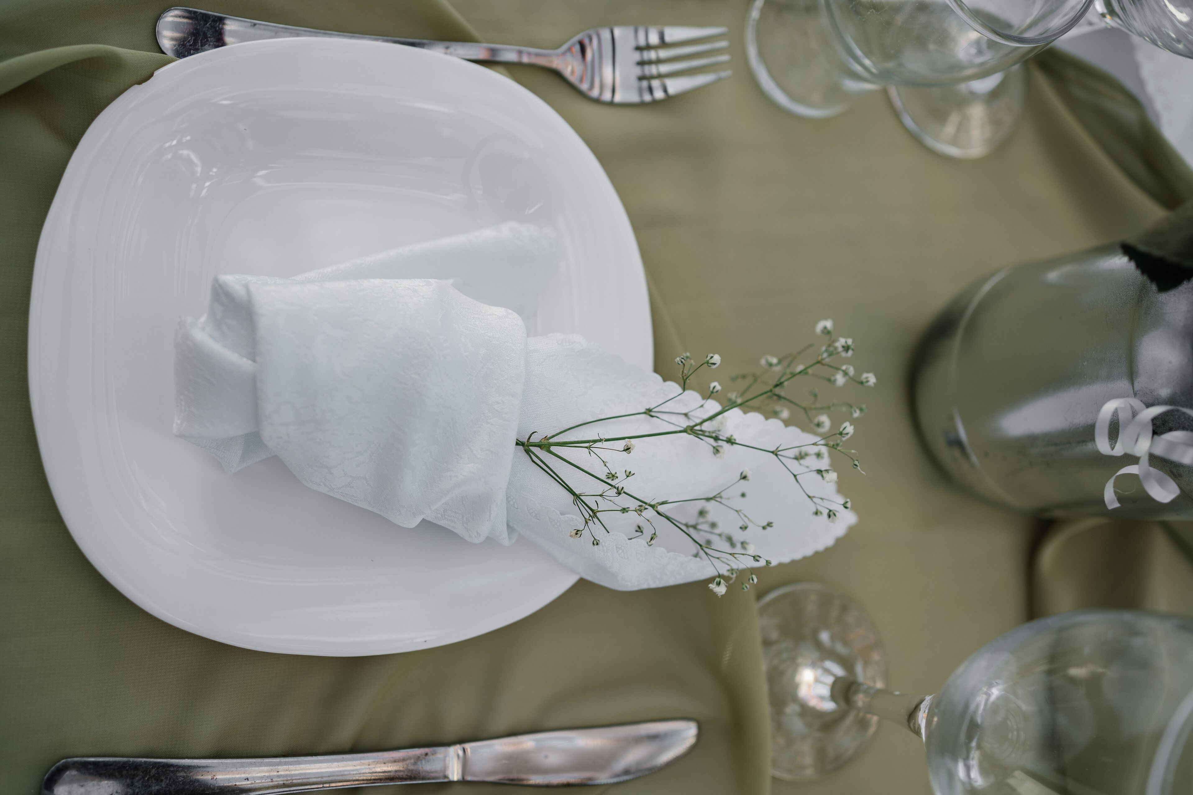 A table set with a white plate, silverware, and clear glassware.