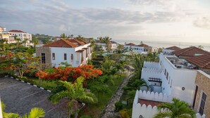 Una zona residencial costera con edificios blancos, un camino pavimentado y abundante vegetación.