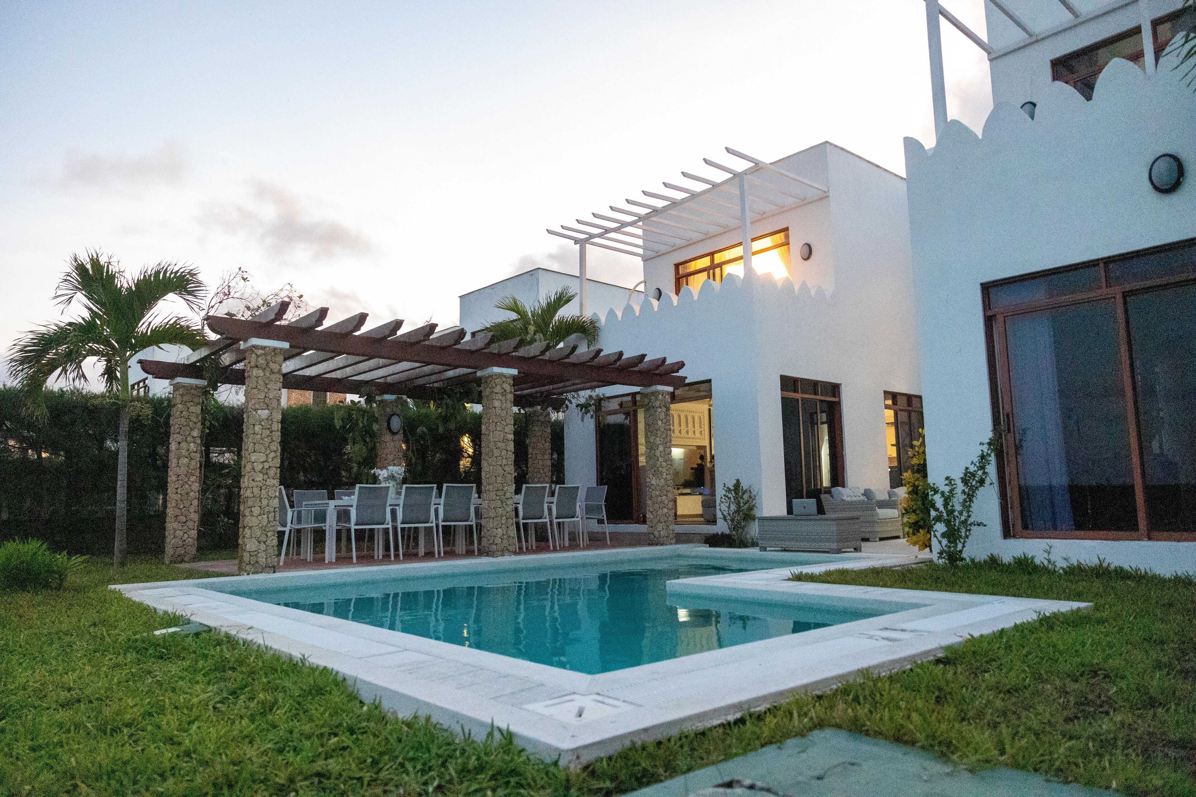 Een modern huis met een zwembad, buitenzitplaatsen en een pergola.