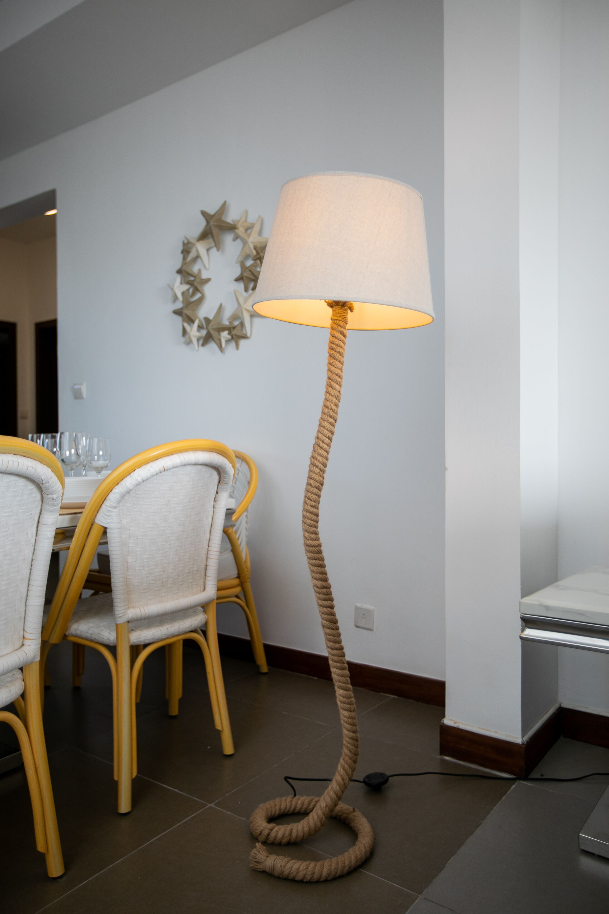 Un coin repas avec une table ronde et des chaises, un lampadaire et un élément décoratif mural.