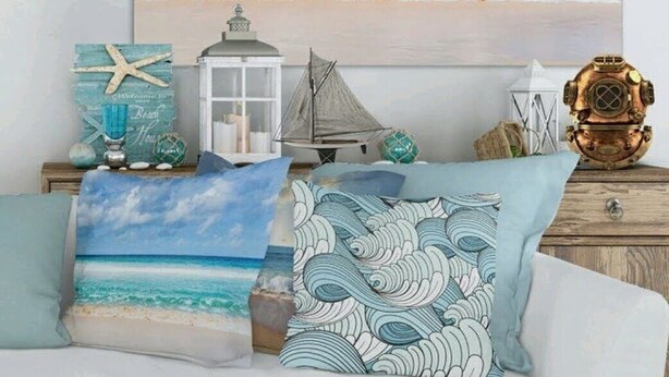 A beach-themed decor with a painting, pillows, and nautical items on a dresser.