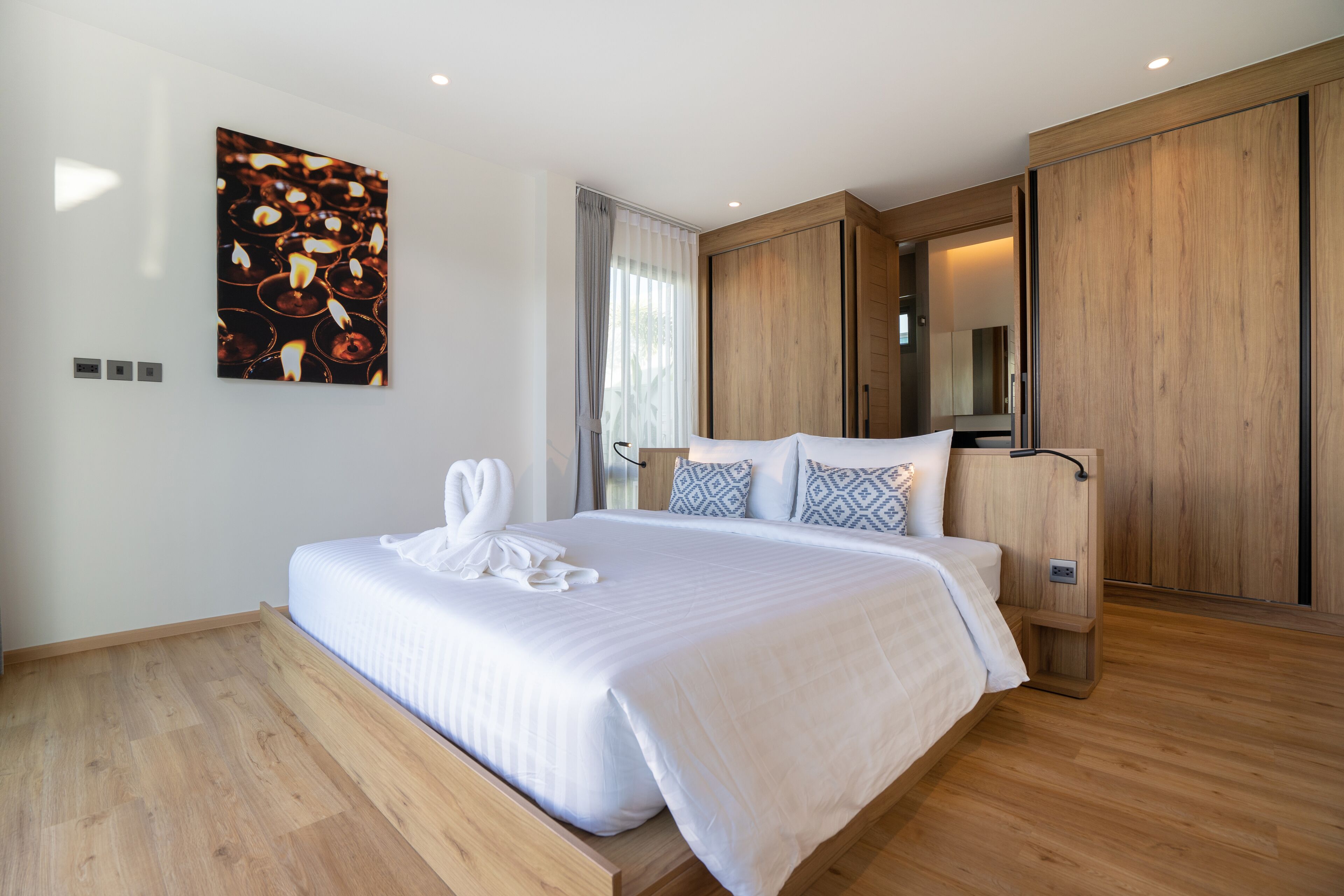 Un dormitorio moderno con una cama grande, suelo de madera, una obra de arte en la pared y un armario.