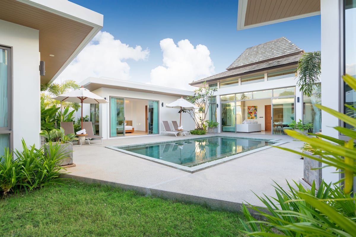 A modern house with a swimming pool, outdoor seating, and lush greenery.