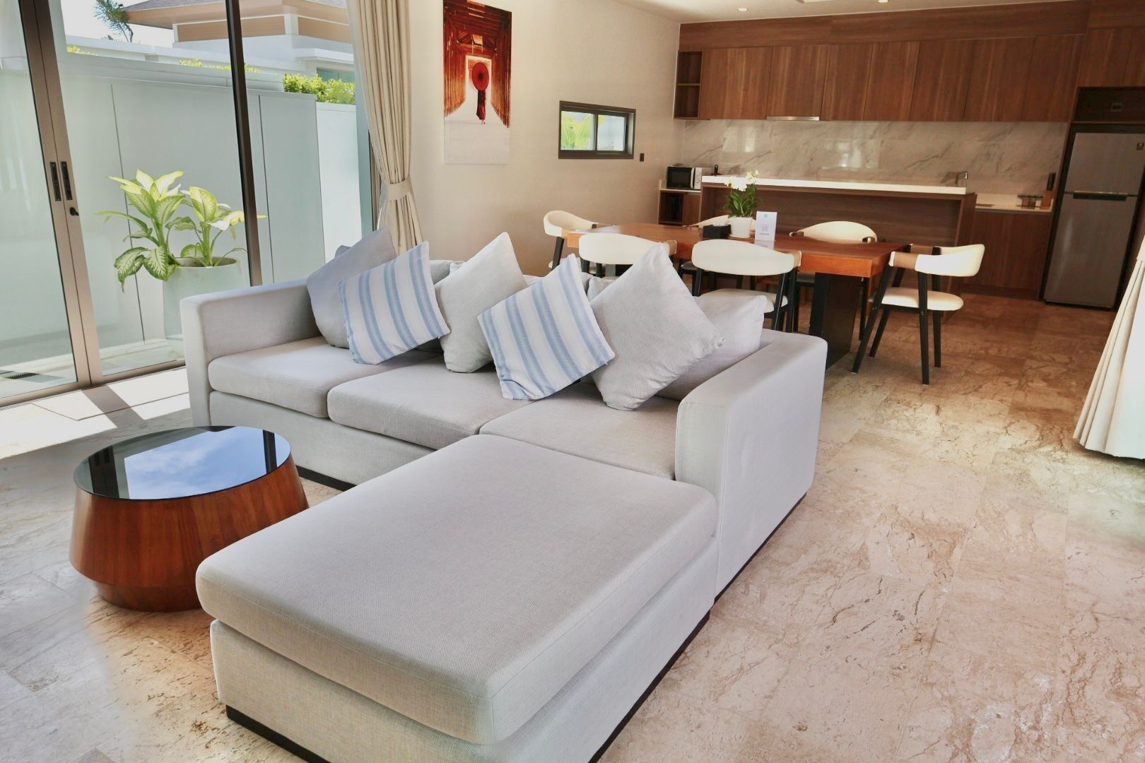 A modern living room with a sofa, a coffee table, and a dining area with a table and chairs.