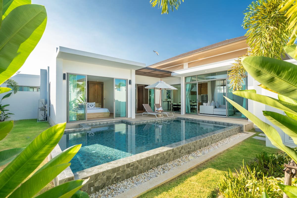 A modern house with a swimming pool, large glass doors, and a patio area.