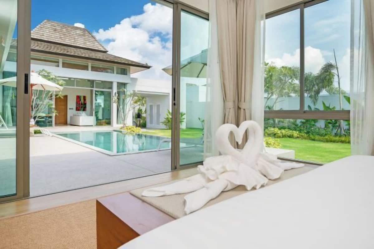 A modern hotel room with a large glass window, a pool, and a heart-shaped decoration.