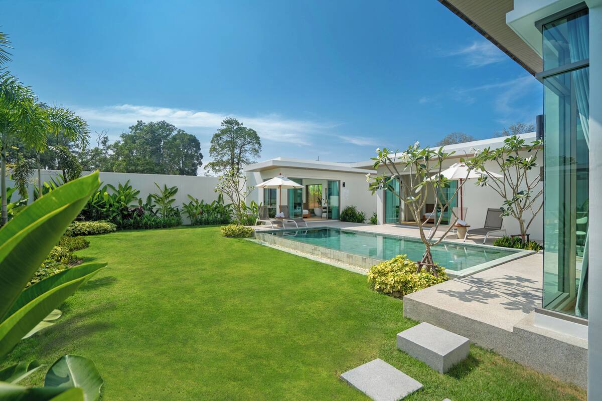 A modern house with a swimming pool, a well-maintained lawn, and a patio area.