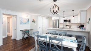 Una cocina moderna con electrodomésticos de acero inoxidable, un comedor con sillas azules y un mapa en la pared.