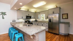 A modern kitchen with granite countertops, stainless steel appliances, and a central island with bar stools.