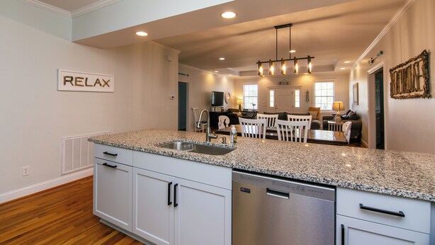 A modern kitchen with granite countertops, white cabinetry, and stainless steel appliances.