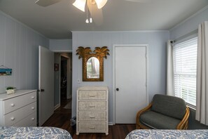 Une chambre à coucher avec un lit, une chaise, une commode, un miroir et une porte.