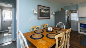 A dining area with a wooden table, four chairs, and a framed picture on the wall.