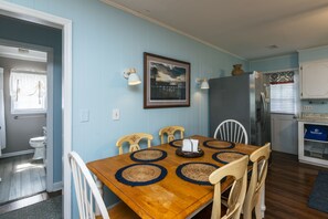 Een eetgedeelte met een houten tafel, vier stoelen en een ingelijste foto aan de muur.