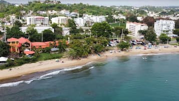 An aerial view of a coastal town with a beach, buildings, and greenery.