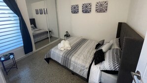 A bedroom with a bed, a bedside table, a mirror, and three wall-mounted artworks. - Lucor D- Eight House (Rincon PR)