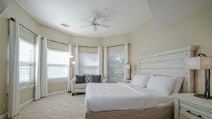 A bedroom with a large bed, a ceiling fan, and a nightstand with a lamp. - Fisherman's Cove- Golf cart included (Miramar Beach)