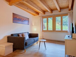 Un salon moderne avec un canapé, une petite table et un téléviseur.