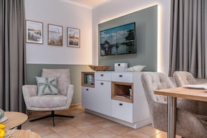 Ein modernes Wohnzimmer mit einer Couch, einem Esstisch und einem Schrank mit Büchern und Dekoration.