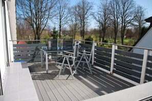 Eine Terrasse mit Metallgeländer, einem Metallstuhl und einem Metalltisch.