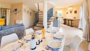 A modern living room with a dining area set for six, a staircase, and a kitchen in the background. - L'Italienne by Interhome (Saint Cyr sur mer Les Lecques)