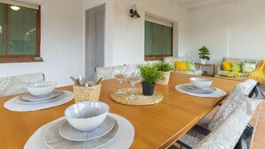 Un coin repas avec une table en bois dressée pour quatre personnes, entourée de sièges rembourrés.