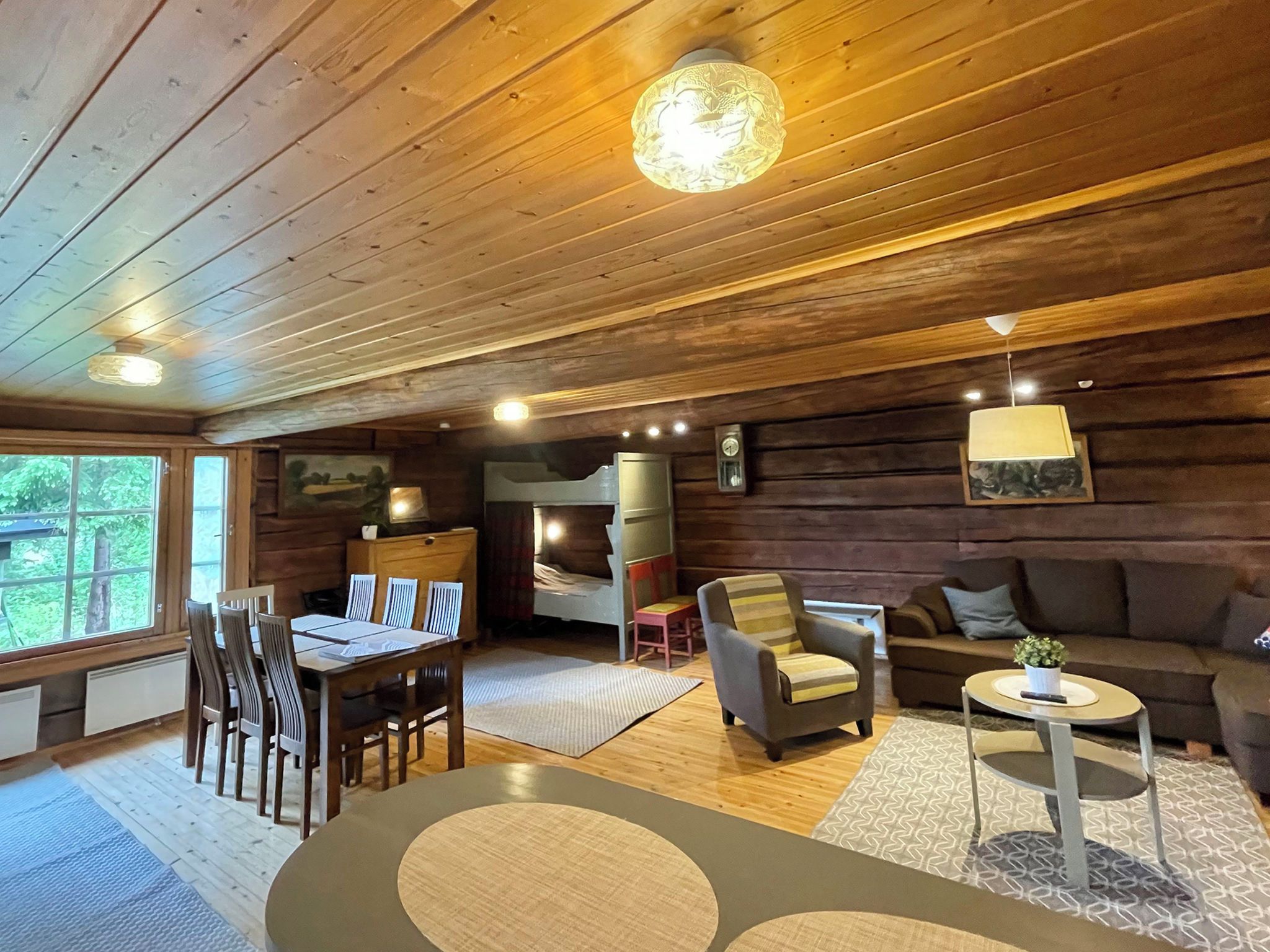 Interior acogedor de una cabaña con comedor, sofá, sillón y una pequeña mesa.