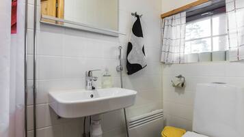 A bathroom with a white sink, mirror, towel rack, toilet, and window with curtains.