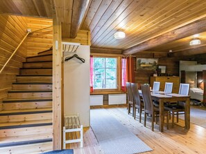 A wooden cabin interior with a staircase, a dining area, and a window with a view of trees. - Metsäpirtti by Interhome (Virrat)