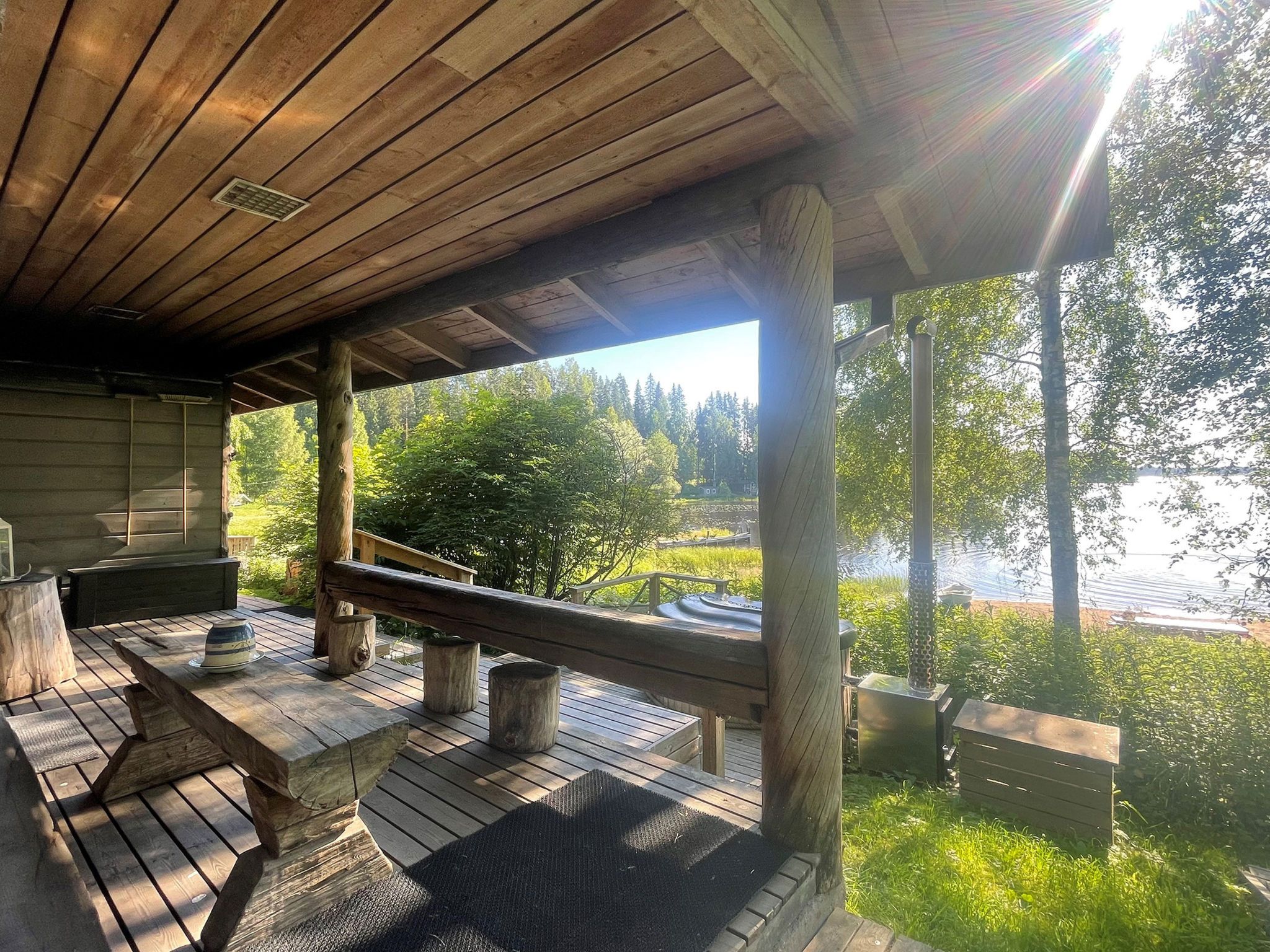 An outdoor wooden deck with benches and a view of a lake surrounded by trees.