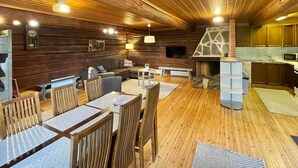 A cozy cabin interior with a dining area, sofa, fireplace, and kitchen. - Metsäpirtti by Interhome (Virrat)