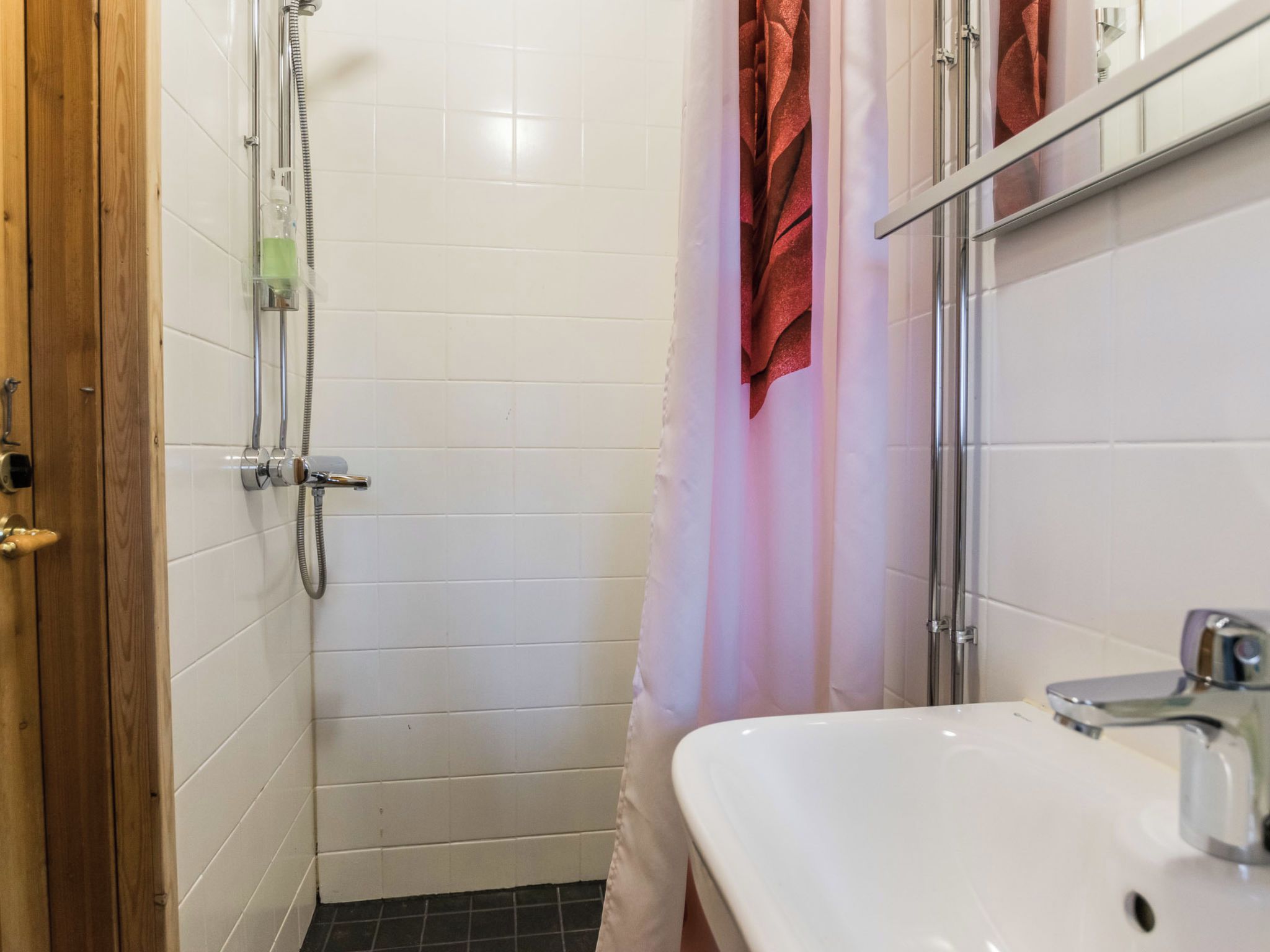 A bathroom with a shower, a sink, and a towel rack.