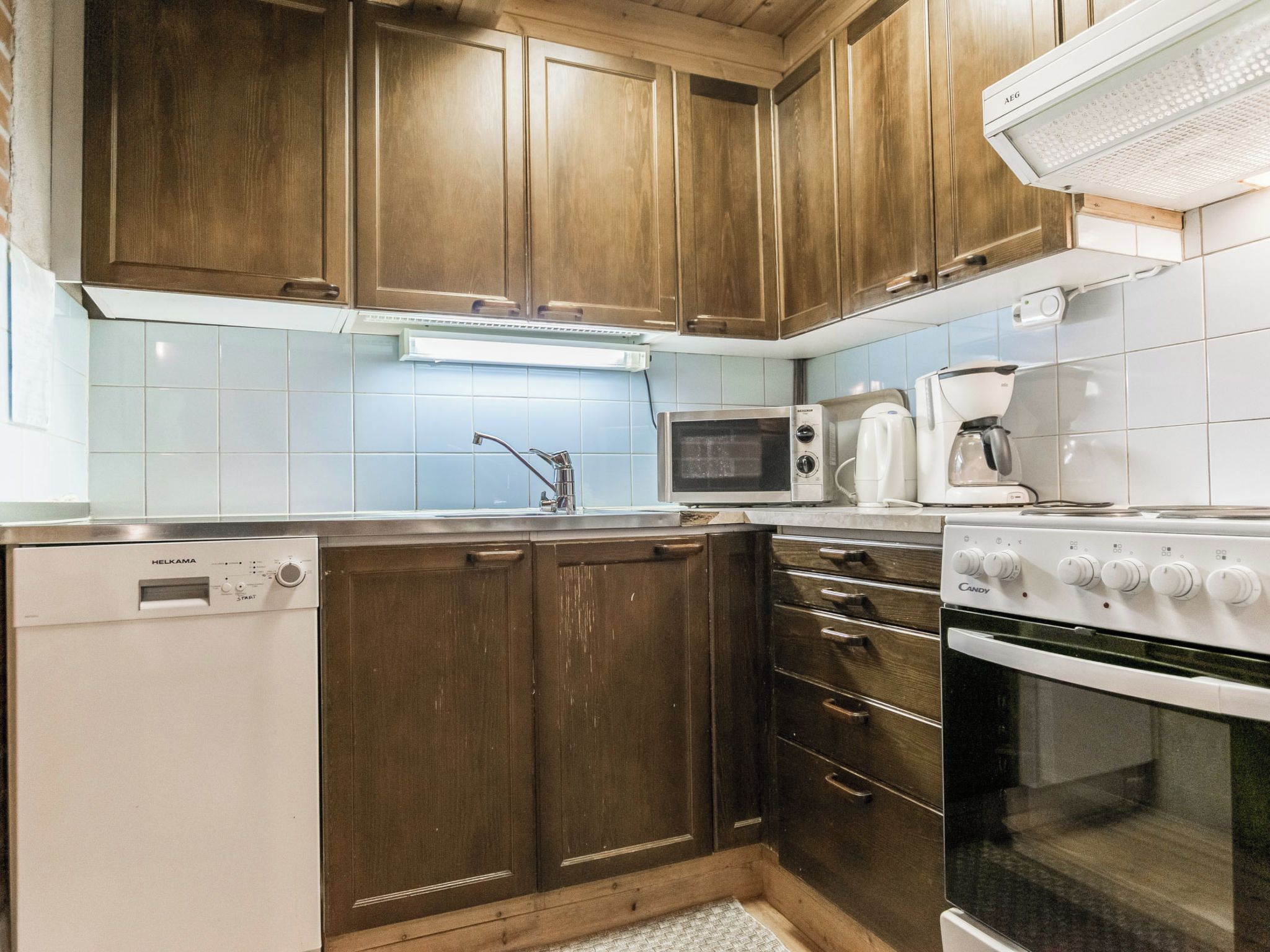 Una cocina con armarios de madera, lavavajillas, microondas, cafetera y horno.