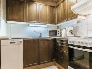 A kitchen with wooden cabinets, a dishwasher, a microwave, a coffee maker, and an oven.