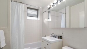 Une salle de bain avec une baignoire, un lavabo, des toilettes, un miroir et une fenêtre.