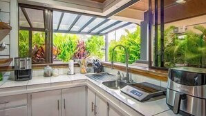 Una cucina moderna con un'ampia finestra, elettrodomestici in acciaio inossidabile e vista su un verde lussureggiante.