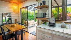 Una cucina moderna con tavolo da pranzo in legno, mobili bianchi e un'ampia finestra vista su un'area verde.