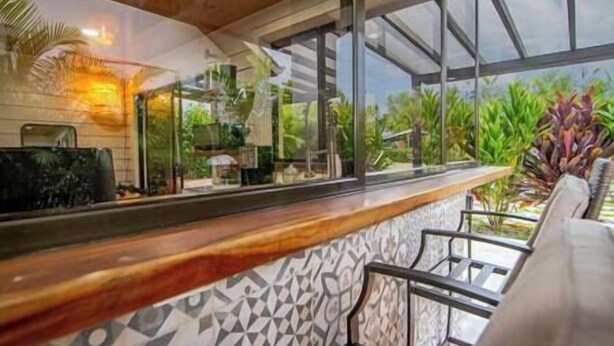 Zona bar con bancone in legno, piastrelle decorate e vista sul verde circostante.