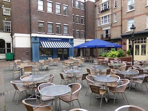 Guests can dine al fresco at this urban hotel's outdoor seating area, surrounded by brick buildings.