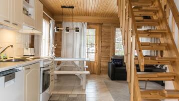 A modern kitchen with white cabinets, a wooden staircase, and a dining area with a bench.