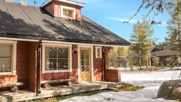 A wooden cabin with a sloped roof, large windows, and a front porch.