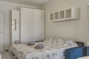 Ein Schlafzimmer mit einem Bett, einem Kleiderschrank und einem an der Wand befestigten Regal.
