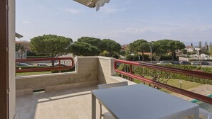Un balcón con vista a un área residencial, una mesa y una baranda.