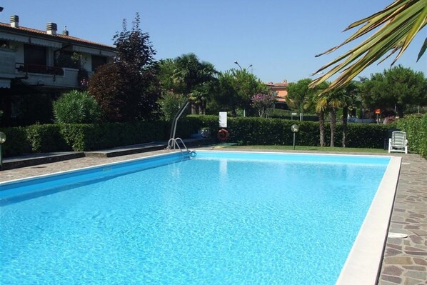 A rectangular swimming pool with a clear blue water surface, surrounded by a stone deck.