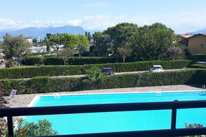 Ein Schwimmbecken mit freiem Blick auf die umliegende Landschaft, darunter Bäume und ferne Berge.