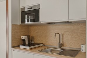 Eine Küche mit Einbauofen, Kaffeemaschine, Spüle und einer Holzrückwand.