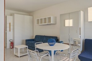 Une pièce moderne avec une table ronde, des chaises, un canapé bleu et une armoire blanche.