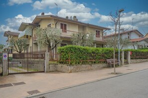 Ein Wohngebäude mit geschlossenem Eingangsbereich, einem Balkon und einem gepflegten Garten.