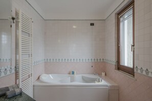 Ein Badezimmer mit einer großen Badewanne, einem Handtuchhalter und einem Fenster.